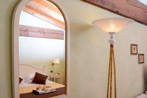 a mirror in a room with a bed and a lamp at Albergo Dimora Storica Antica Hostelleria in Crema