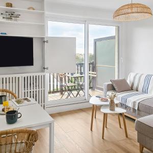 a living room with a couch and a tv at South-facing terrace, direct beach access in Cabourg +21 photos