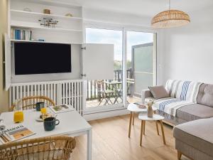 a living room with a couch and a tv at South-facing terrace, direct beach access in Cabourg