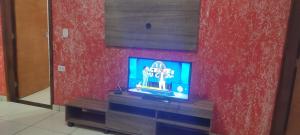 a television in a room with a red wall at Casa em Presidente Prudente in Presidente Prudente