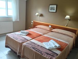 zwei Betten in einem Hotelzimmer mit Handtüchern darauf in der Unterkunft Hostal León II in Porto do Son + 17 Fotos
