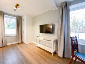 a living room with a television and a desk with a chair at Gästehaus Alte Bücherei in Mittelangeln