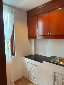 a kitchen with wooden cabinets and a sink and a window at Chook Dee Resort phangan palm beach in Ban Tai