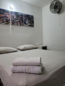 a white bed with two towels on top of it at Hmetrohotel in Medellín +8 photos