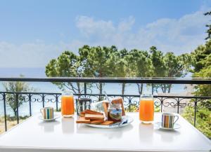 a white table with food and drinks on a balcony at Theodora Apartments in Avía