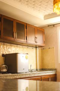 a kitchen with wooden cabinets and a microwave at Tamraght Apartement Sea View in Agadir