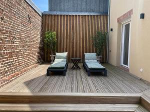 a patio with two benches and a table on a building at Le Bras d 'Or in Pont-lʼÉvêque