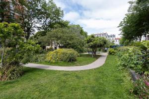 a walkway in a park with grass and trees at 4-room apartment Place de la Mairie - City Center in Bois-Colombes