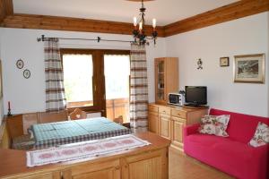 a living room with a red couch and a tv at Appartamenti Piller Roner Roberto in Sappada