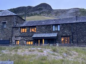 a stone house with a mountain in the background at Swirral Edge Cottage in Penrith