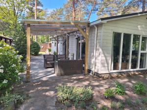 a patio with two wicker chairs under a pergola at Luxe 5 pers chalet natuurlijk gelegen in IJhorst