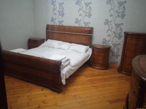 a bedroom with a bed with white sheets and wooden furniture at Sweet dreams in Baku