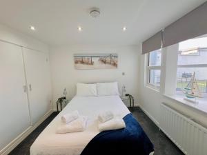 a white bedroom with a large bed with two pillows at The Barbican Penthouse in Plymouth