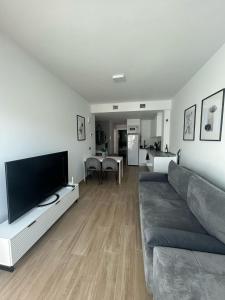 a living room with a couch and a flat screen tv at A top-floor modern apartment Located 100 meters from the beach in Fuengirola