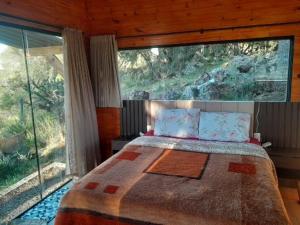a bedroom with a bed and a large window at Chale VITRUM in Urupema