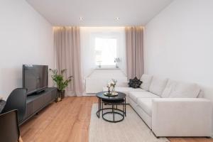 a living room with a white couch and a tv at BYTOM One 24H Strefa Komfortu in Bytom