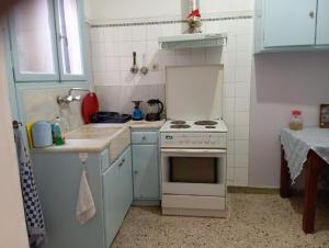 a white kitchen with a stove and a sink at Comfort bed in a room 5' from metro in Athens