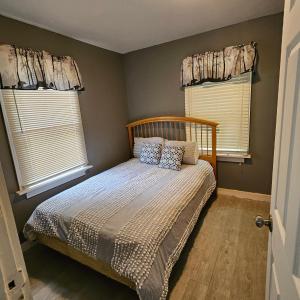 a bedroom with a bed with pillows and two windows at The Honey Bear Cabins in Lincoln Junction
