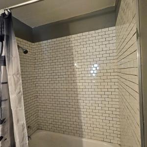 a bathroom with a shower with a white tiled wall at The Honey Bear Cabins in Lincoln Junction +103 photos