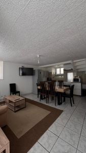 a living room with a table and chairs and a kitchen at Petite maison de bourg in Broons