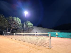 two people playing tennis on a tennis court at night at Apartman Bela in Matulji