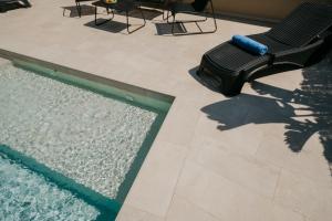 a shadow of a person sitting on a chair next to a swimming pool at Villa Victoria Paradise in Cala en Blanes
