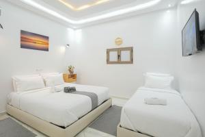 deux lits dans une chambre aux murs blancs dans l'établissement Résidence America, à Dakhla