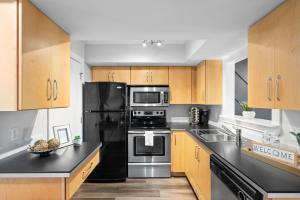 Una cocina con electrodomésticos de acero inoxidable y gabinetes de madera. en The Lofts of Downtown - 540 N 2nd St - Unit 202 - Charming 2-Bedroom in the Heart of Clarksville TN, en Clarksville