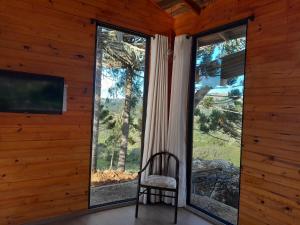 a chair in a room with a large window at Chale VITRUM in Urupema