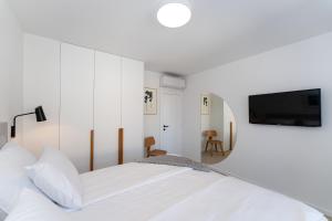 a white bedroom with a bed and a flat screen tv at House Tre Venti with pool in Sveti Filip i Jakov +61 photos