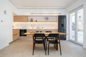 a kitchen with a wooden table and black chairs at House Tre Venti with pool in Sveti Filip i Jakov
