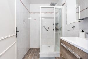 a white bathroom with a shower and a sink at Appartement lumineux et cosy à 15min de Paris in Antony