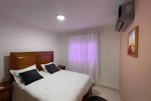 a bedroom with a bed with white sheets and black pillows at Sunshine Palmares de Caleta in La Romana +40 photos