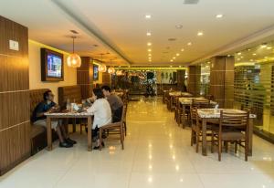 Eine Gruppe von Menschen sitzt an Tischen in einem Restaurant in der Unterkunft Hotel Dali Plaza Ejecutivo in Guadalajara