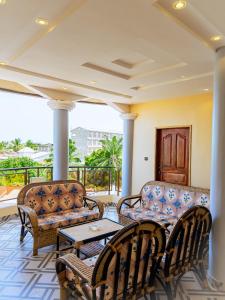 a porch with two couches and a table and chairs at Maison Kaléta Guest House in Godomey