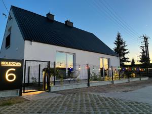 a white house with a fence in front of it at Apartamenty CEKCYN - KOLEJOWA 6 in Cekcyn