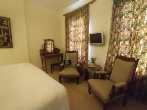 チェルトナムにあるBadger Towersのベッドと椅子2脚とテレビのある寝室