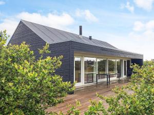 a black house with a deck in front of it at 4 star holiday home in Brovst in Brovst
