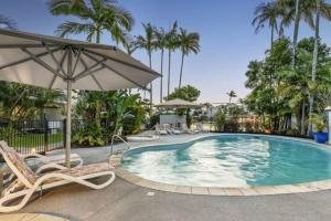 a swimming pool with chairs and an umbrella at Noosa Keys Apartments in Noosaville