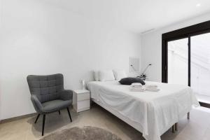 ein weißes Schlafzimmer mit einem Bett und einem Stuhl in der Unterkunft Sunny luxury corner house with private pool in San Pedro del Pinatar + 16 Fotos