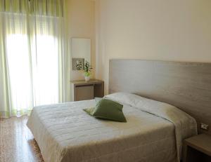 a bedroom with a bed with a green pillow on it at Hotel Rosa Del Tirreno in Quercianella
