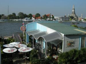 バンコクにあるオーラム ザ リバー プレイスの水辺のテーブルと傘のある建物