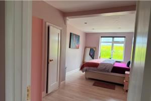 a bedroom with pink walls and a bed with a window at Cherry Chirp Cottage in County Fermanagha in Garrison