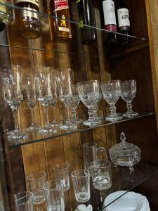 a bunch of glasses sitting on a shelf with wine bottles at Casa das Palmeiras Pousada in Treviso