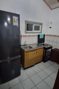 a kitchen with a black refrigerator and a sink at Yenú Aiken in Coihaique