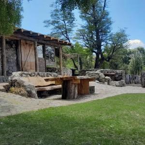 einem Picknicktisch aus Holz in einem Park mit einer Bank in der Unterkunft Haras Casa de Campo in San Martín de los Andes + 4 Fotos