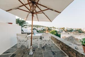 a table and chairs on a balcony with an umbrella at Yiayias Home Sifnos in Apollonia