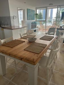 mesa de madera con sillas blancas y comedor en Cozy room with Ocean Views, en Gold Coast