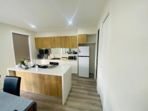 a kitchen with a white refrigerator and a counter at Luxe Nest in Rockbank
