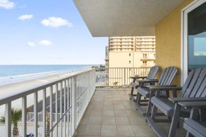 a balcony with chairs and a view of the beach at A Wave From it All Oceanfront Pool Condo in Daytona Beach